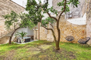 Une cour intérieure avec un mur en pierre, un arbre, un jacuzzi et deux chaises.