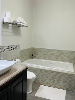 A bathroom with a bathtub, toilet, and a sink. - Garden City Suite | Modern 2BR Apartment (Belmopan)