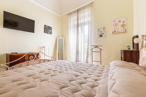 Ein Schlafzimmer mit einem großen Bett, einem Fernseher an der Wand, einem Spiegel und Kunstwerken an den Wänden.