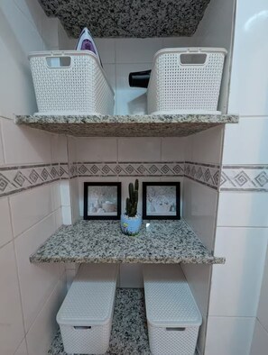 Ein Badezimmer mit einer Granitplatte, weiß gefliesten Wänden und einer Kakteenpflanze.