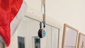 Olohuoneessa on harmaa sohva, punainen kaappi ja seinällä on kehystetty valokuva rannalta.