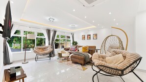 Een moderne woonkamer met een bank, fauteuil, hangstoel en een flatscreen televisie.