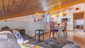 Un salon chaleureux avec un canapé, une table à manger et des chaises, et un coin cuisine visible à travers une porte ouverte.