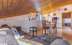 Un salon chaleureux avec un canapé, une table à manger et des chaises, et un coin cuisine visible à travers une porte ouverte.