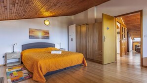 Une chambre à coucher comprenant un lit, des tables de chevet, une lampe fixée au mur, un tableau et une armoire.