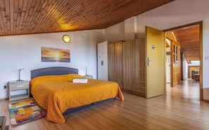Une chambre à coucher comprenant un lit, des tables de chevet, une lampe fixée au mur, un tableau et une armoire.