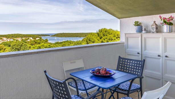 Un balcon avec une table, des chaises et une vue sur la côte.
