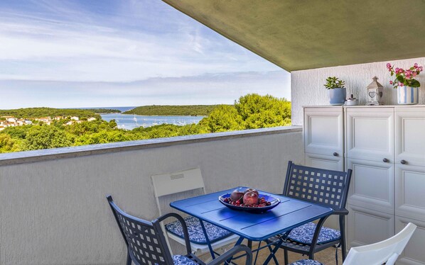 Un balcon avec une table, des chaises et une vue sur la côte.