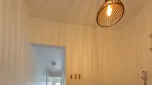 Ein Flur mit Holzboden, ein Essbereich mit rundem Tisch und Stühlen sowie eine hängende Leuchte.