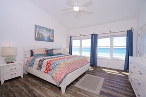 A bedroom with a bed, a nightstand, a dresser, a ceiling fan, and a window with curtains. - Beachfront Townhouse(10) Pet Friendly Covered Deck (Panama City Beach)