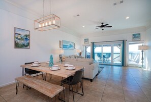 A dining area with a wooden table, chairs, and a bench. There is a ceiling fan and a view of the outside. - Beachfront Townhouse(10) Pet Friendly Covered Deck (Panama City Beach)