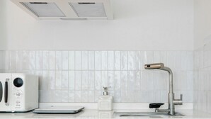 Une cuisine avec un plan de travail blanc, un grille-pain, un robinet et des placards bleu clair.