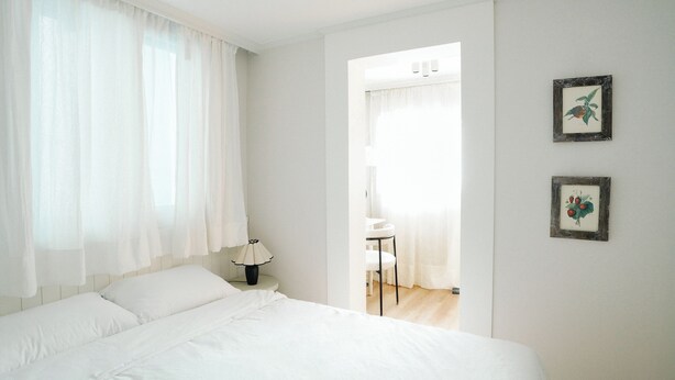 Une chambre à coucher avec un lit, une table de chevet, une lampe et deux tableaux encadrés accrochés au mur.
