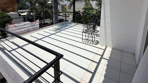 A covered outdoor patio with tiled flooring, metal railings, and outdoor furniture. - Arroyito: Small Apartment (Puerto Vallarta)
