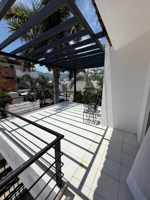 A covered outdoor patio with tiled flooring, metal railings, and outdoor furniture. - Arroyito: Small Apartment (Puerto Vallarta)
