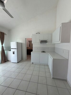 A kitchen with white cabinets, a refrigerator, and a ceiling fan. - Arroyito: Small Apartment (Puerto Vallarta)