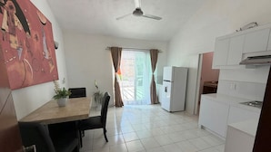 A modern kitchen with white cabinets, a dining area with a table and chairs, and a ceiling fan. - Arroyito: Small Apartment (Puerto Vallarta)