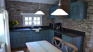 Una cocina con armarios azules, una mesa de madera y lámparas colgantes.