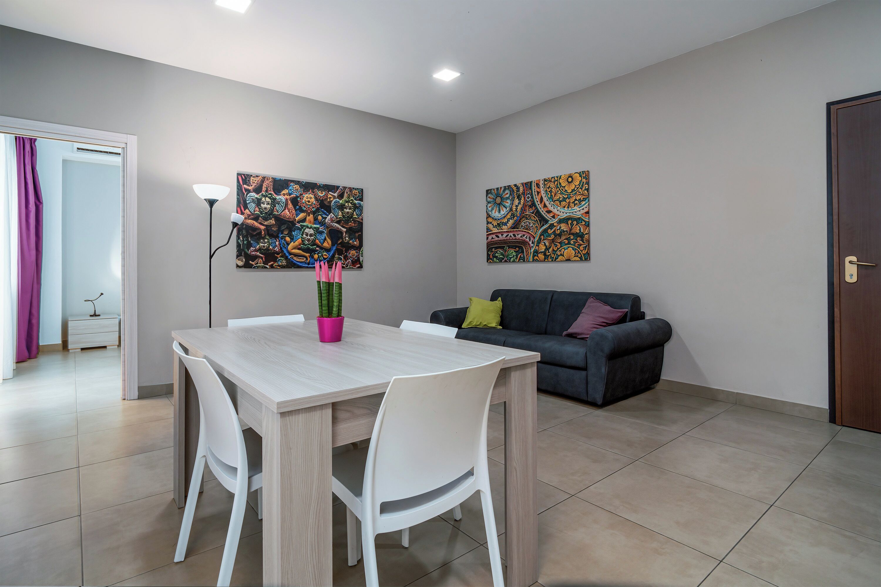 Ein Essbereich mit Tisch, Stühlen, einer Couch und zwei Bildern an der Wand.