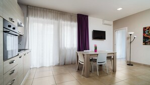 Eine moderne Küche mit Essbereich, einem Flachbildfernseher und einer Stehlampe.