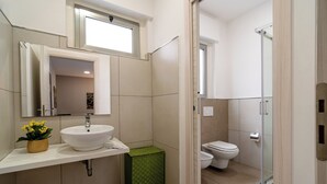 Ein Badezimmer mit Waschbecken, Spiegel, Toilette und Dusche.