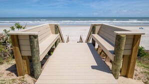 A wooden boardwalk leading to a beach with a clear view of the ocean. - Sand Dollar 103 (St. Augustine)