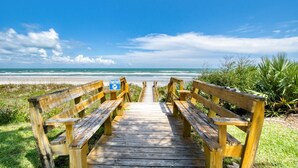 A wooden boardwalk leading to a beach with benches and a sign warning about sea turtles. - Sand Dollar 103 (St. Augustine)