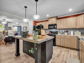 A modern kitchen with wooden cabinets, a central island, and pendant lighting. - Peaceful Mountain Retreat | Wraparound Deck (Black Mountain)