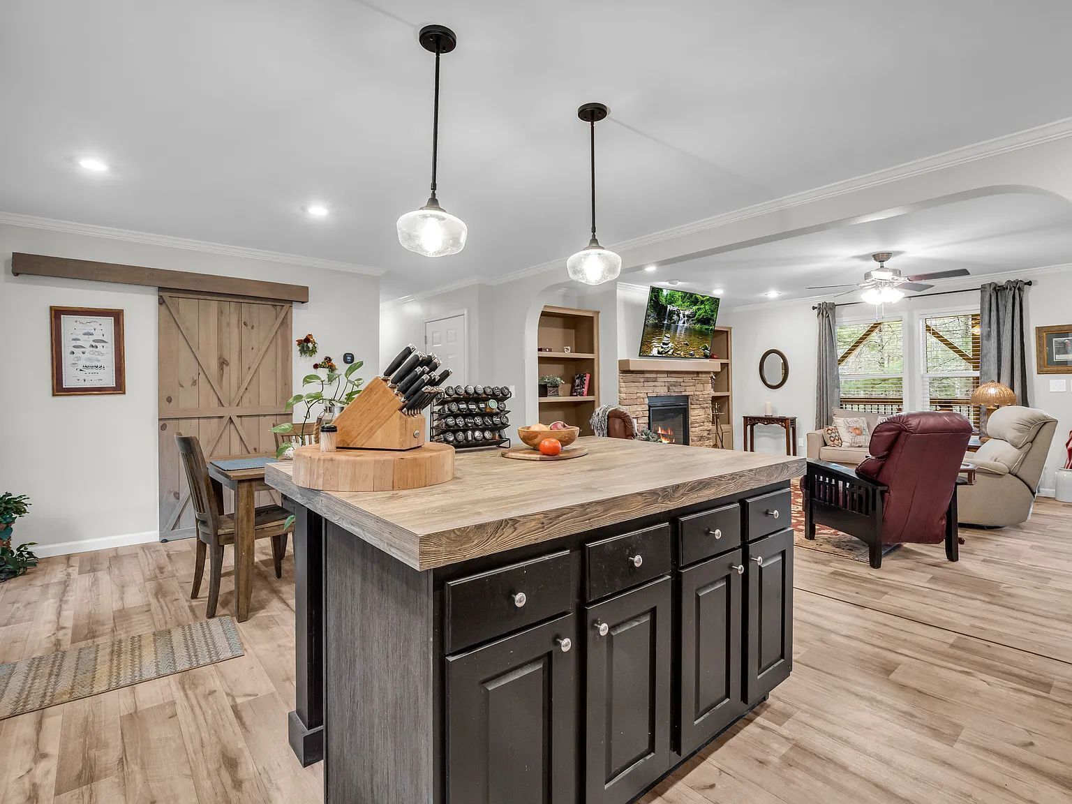 A kitchen with a central island, wooden flooring, and pendant lighting.