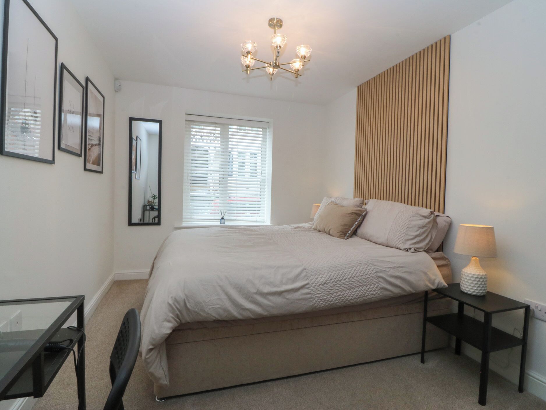 Un dormitorio con cama, mesitas de noche, escritorio y silla.