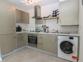 Una cocina moderna con horno integrado, lavadora y campana extractora de acero inoxidable.