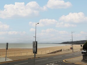 Eine Küstenstraße mit Strand im Hintergrund, einem Fußweg und einer Ampel.