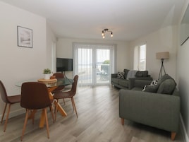 Una sala de estar moderna con una mesa de comedor de vidrio, un sofá y un televisor.