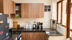 Una cucina moderna con mobili in legno, un frigorifero nero, una macchina da caffè e un lavello.
