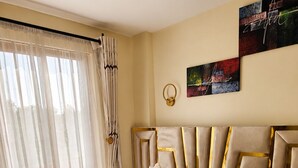 Una camera d'hotel con un letto, tende, un quadro e una luce decorativa a parete.