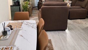 Un soggiorno moderno con un divano, un tavolo da pranzo con sedie, una macchina del caffè e una TV.