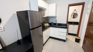 Una cocina compacta con refrigerador, pileta y una mesada pequeña.