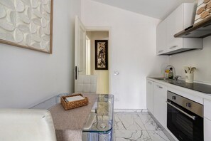 A modern kitchen with a marble floor, a built-in oven, and a stainless steel range hood. - Forte Privé • Apartment with Private Garden (Forte dei Marmi)