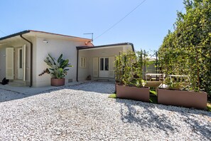 A house with a gravel driveway, a potted plant, and a garden area with a trellis. - Forte Privé • Apartment with Private Garden (Forte dei Marmi)