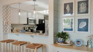 Een moderne keuken met witte kasten, een zwarte koelkast en een hangende lamp.