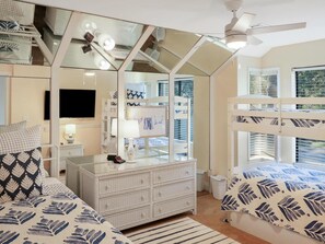 Ein Schlafzimmer mit Etagenbetten, einem Schminktisch, einem Fernseher und einem Fenster mit Jalousien.