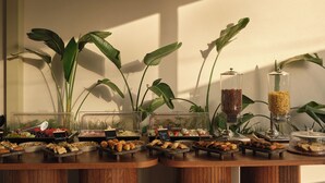 Disposição de buffet com diversos alimentos e um dispensador de café.