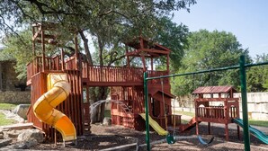 Ein Spielplatz mit Rutsche, Schaukeln und einer Kletterkonstruktion.