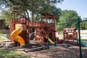 Ein Spielplatz mit Rutsche, Schaukeln und einer Kletterkonstruktion.