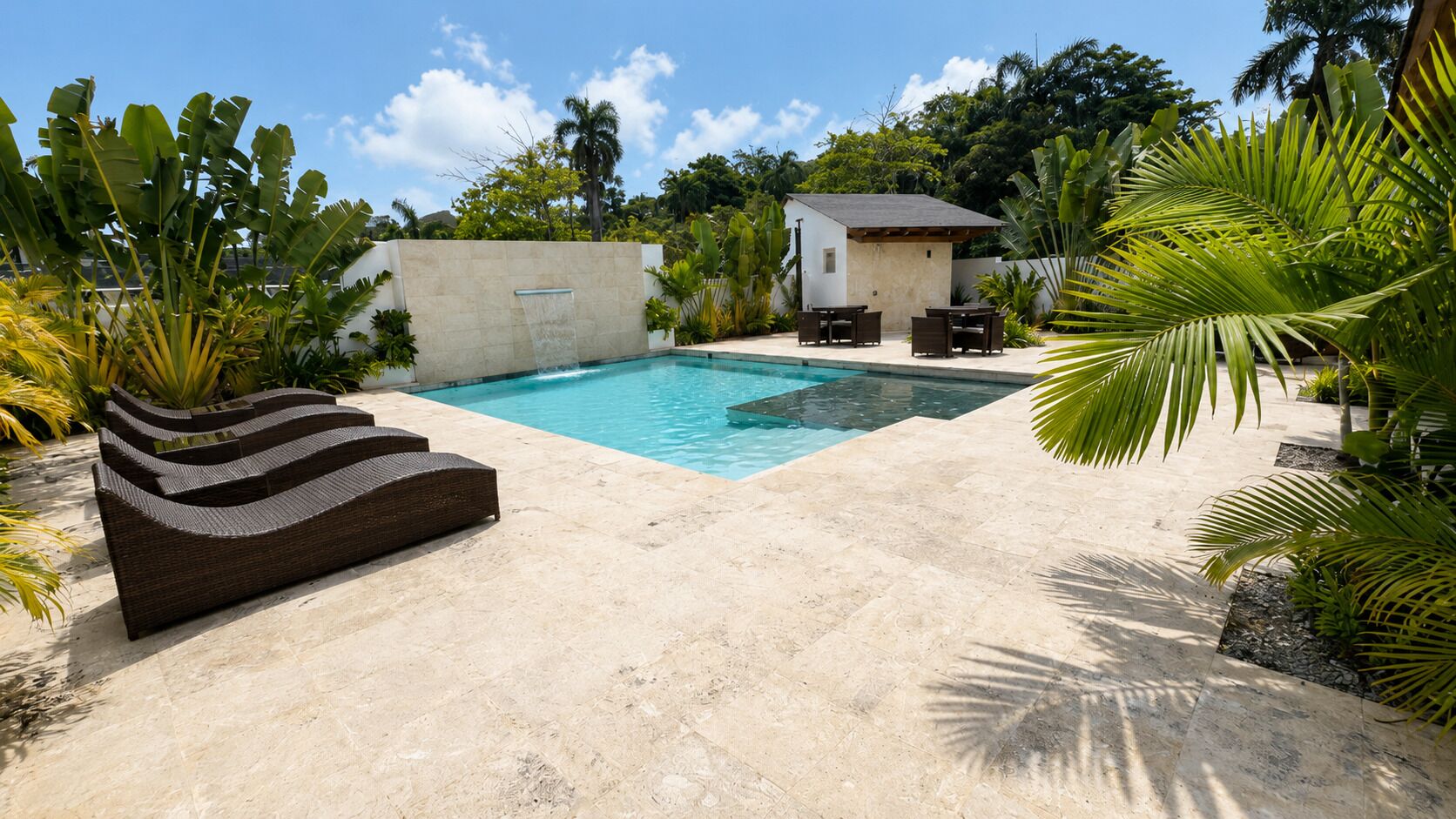A swimming pool with a stone deck, a small building, and outdoor furniture.