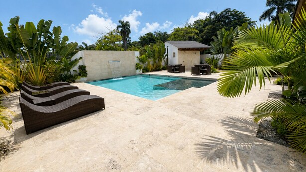 Una piscina con cubierta de piedra, un edificio pequeño y mobiliario de exterior.