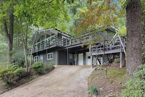 Ein modernes Haus mit einer Schotterauffahrt, umgeben von Bäumen.