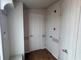 A hallway with two doors, a wooden floor, and a white wall.