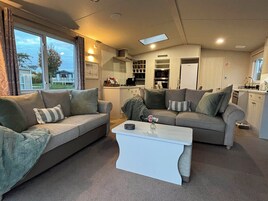 Un espacio habitable compacto con dos sofás, una mesa de centro y una zona de cocina.