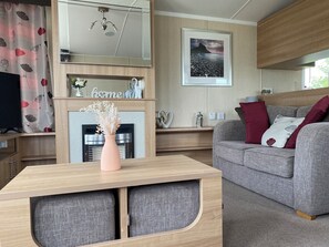 Ein modernes Wohnzimmer mit Kamin, einer Couch, einem Couchtisch und einem an der Wand befestigten Fernseher.